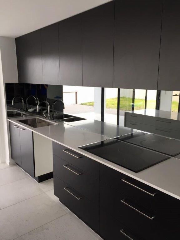 A Kitchen With Black Cabinets And White Counter Tops — Frameless Shower Installations In Maroochydore, QLD