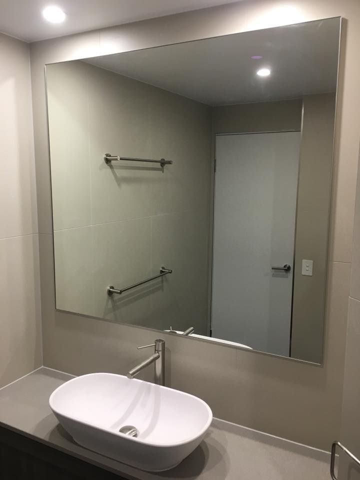 A Bathroom With a Sink and a Large Mirror — Frameless Shower Installations In Mooloolaba, QLD