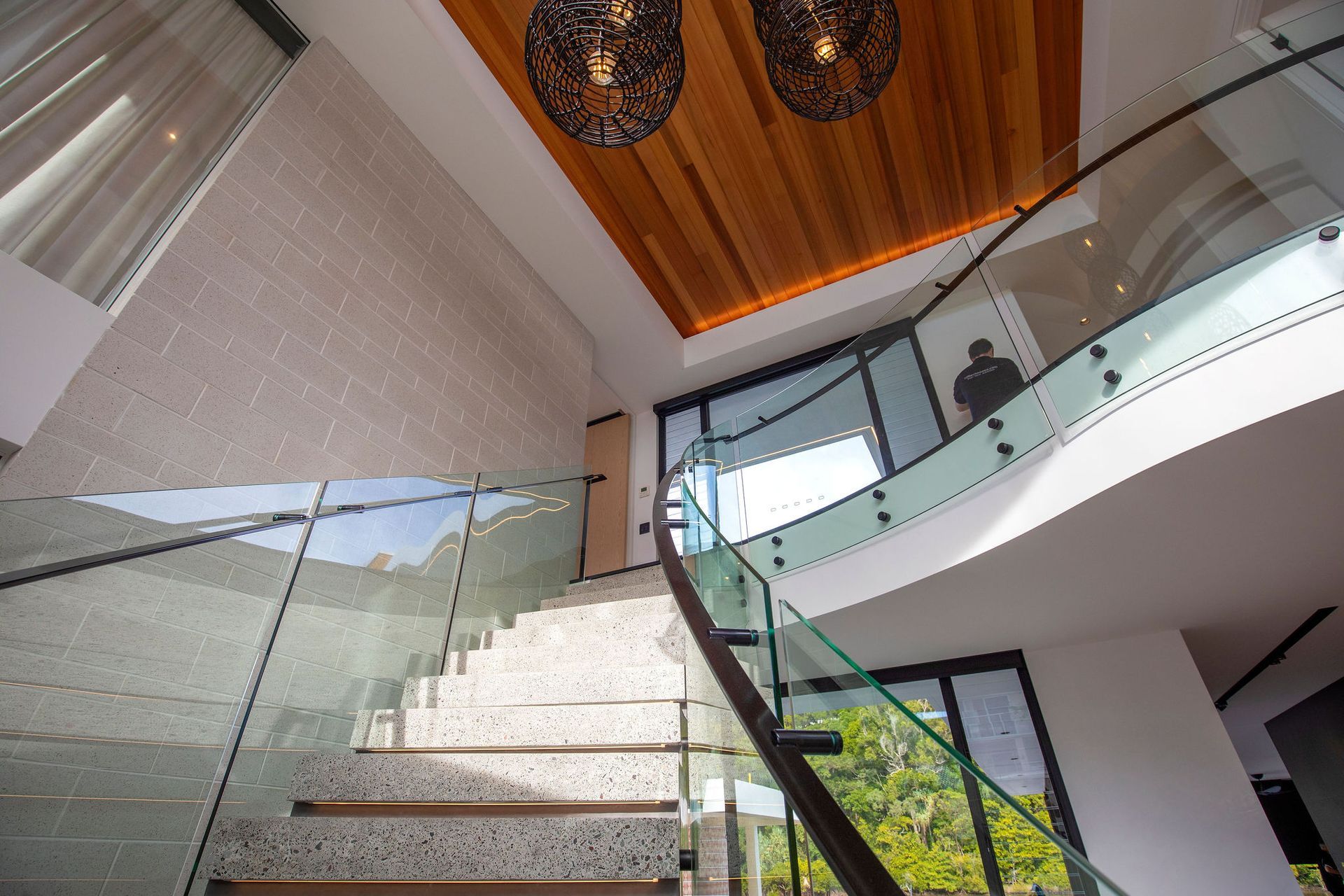 A Balcony With a Glass Railing and Trees in the Background — Frameless Shower Installations In Maroochydore, QLD