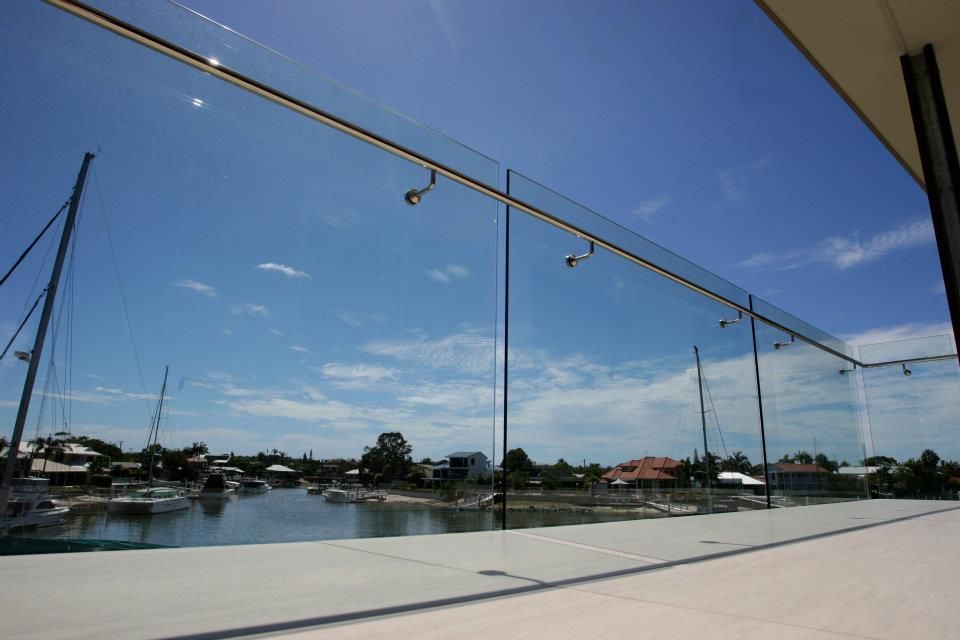 A Balcony With a Glass Railing Overlooking a Body of Water — Frameless Shower Installations In Noosa, QLD