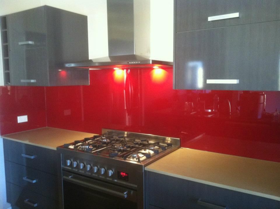 A Kitchen With Red Cabinets and a Stove Top Oven — Frameless Shower Installations In Noosa, QLD