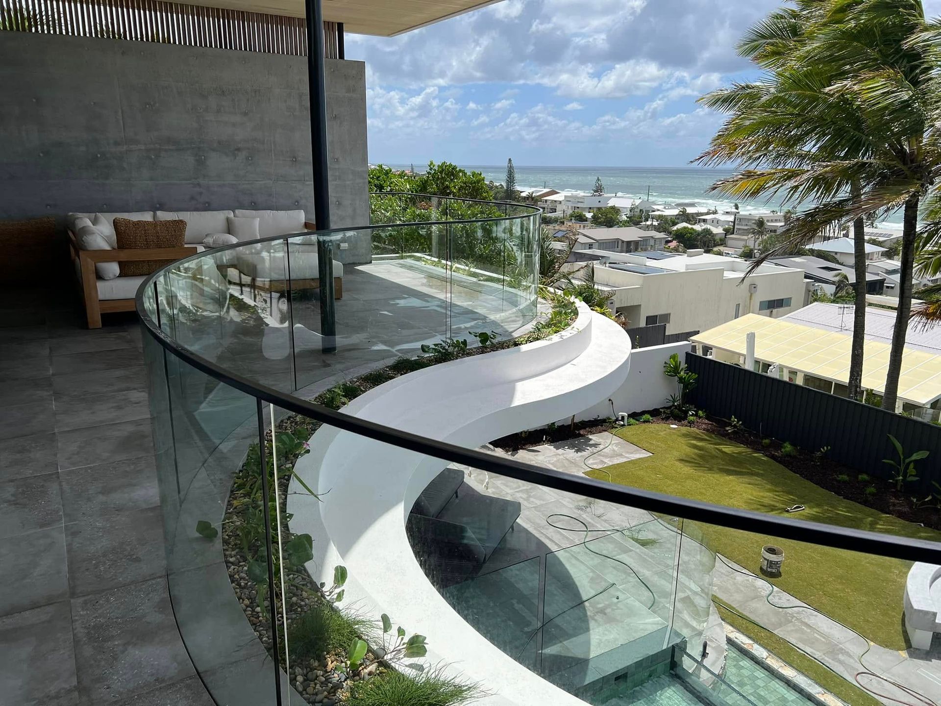 Balcony With Glass Railing Overlooking a Coastal Town— Frameless Shower Installations, Sunshine Coast