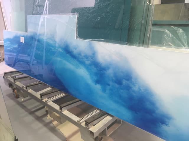 A Large Piece of Glass With a Picture of a Wave on It — Frameless Shower Installations In Maroochydore, QLD