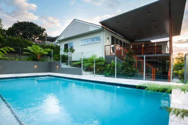 A Large Swimming Pool Surrounded By A Glass Fence In A Backyard — Frameless Shower Installations In Maroochydore, QLD