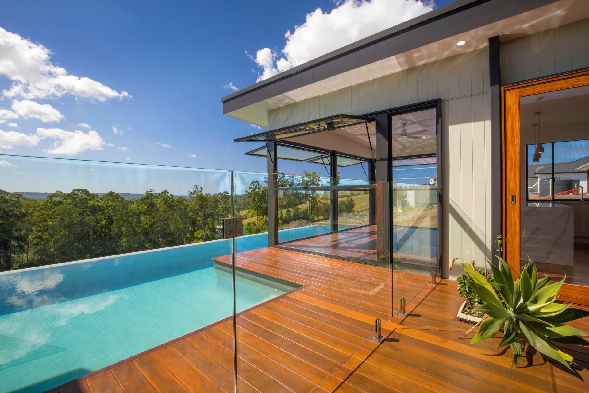 A Large Swimming Pool is Surrounded by a Glass Fence — Frameless Shower Installations In Maroochydore, QLD