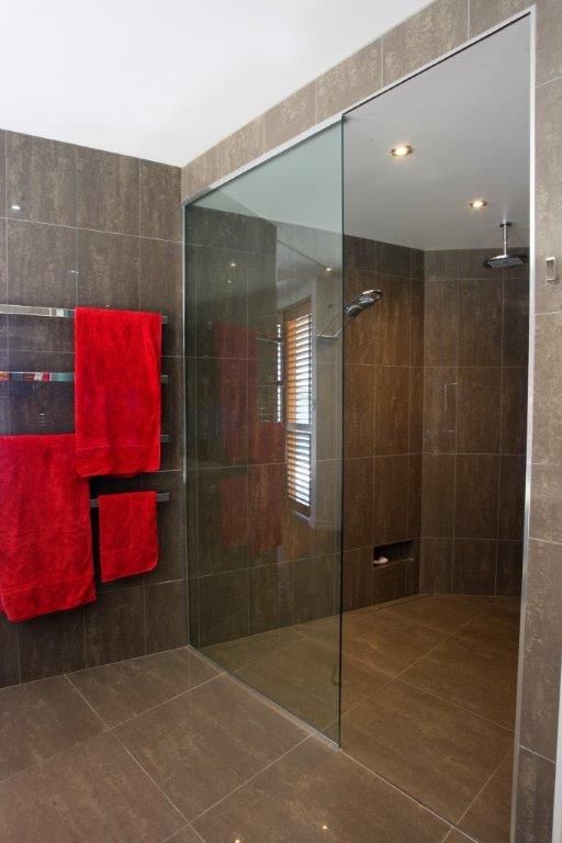A Bathroom With a Walk in Shower and Red Towels — Frameless Shower Installations In Maroochydore, QLD