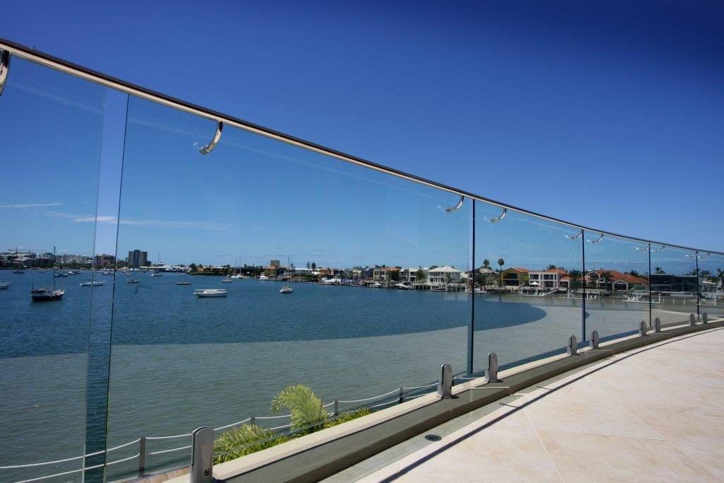 A Glass Railing Overlooking a Body of Water With Boats in It — Frameless Shower Installations In Maroochydore, QLD