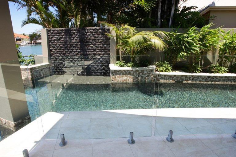 A Large Swimming Pool With a Glass Fence Around It — Frameless Shower Installations In Maroochydore, QLD