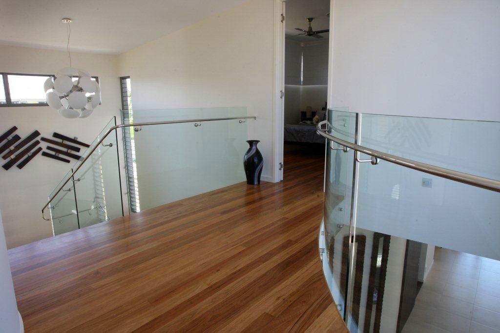 A Staircase With a Glass Railing and Wooden Floors in a House — Frameless Shower Installations In Maroochydore, QLD