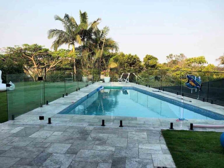 A Large Swimming Pool Surrounded By A Glass Fence In A Backyard — Frameless Shower Installations In Maroochydore, QLD