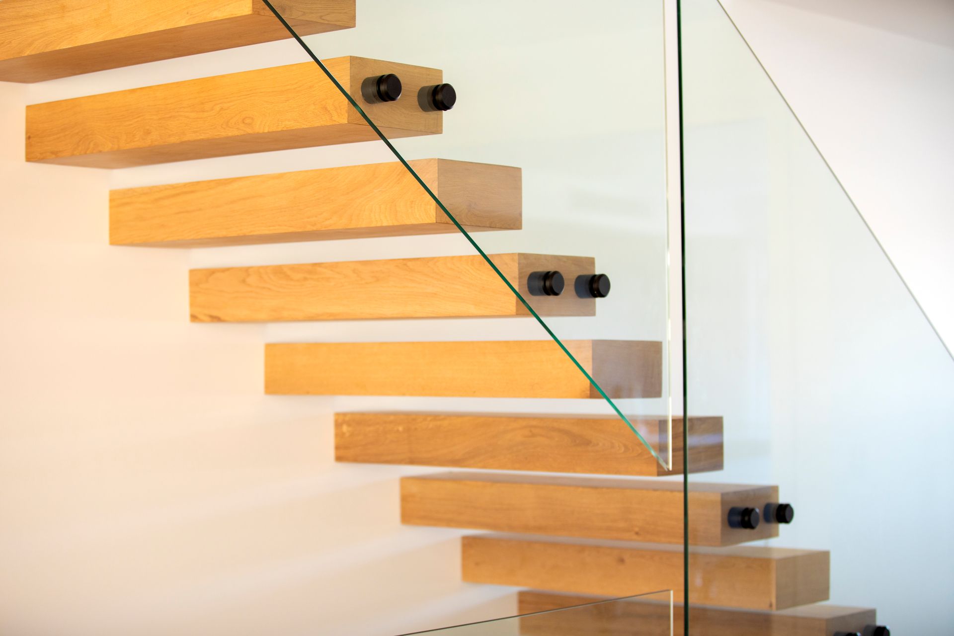 A Wooden Staircase With a Glass Railing and a Window — Frameless Shower Installations In Caloundra, QLD