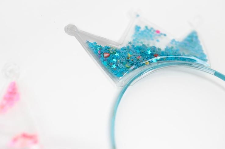 A close up of a headband in the shape of a crown filled with blue glitter.