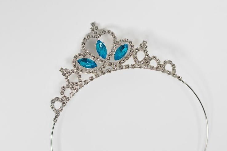 A silver tiara with blue stones on a white background.