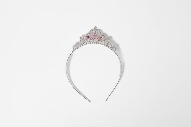 A white headband with a pink tiara on it on a white background.