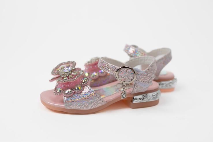 A pair of pink sandals with bows on them on a white background.