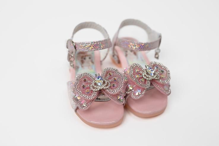 A pair of pink sandals with bows on them on a white background.