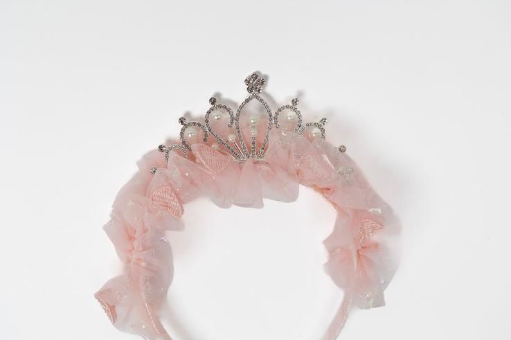A pink headband with a crown on it on a white background.