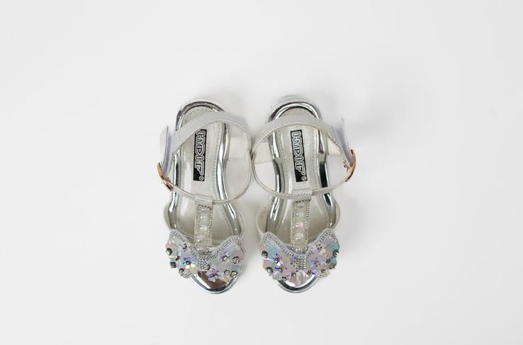 A pair of silver sandals on a white background.