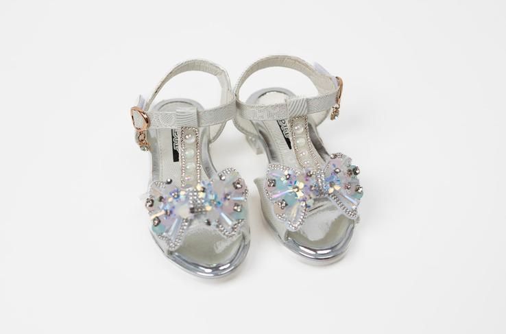A pair of silver sandals on a white background.