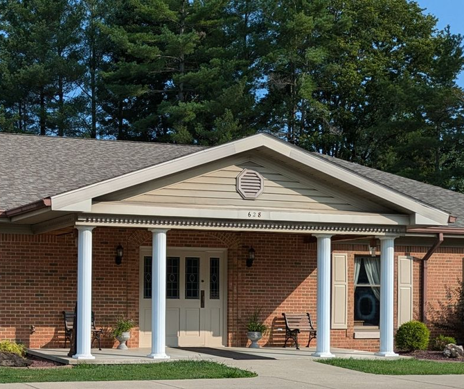 The front door of a house with a porch and plants in front of it.