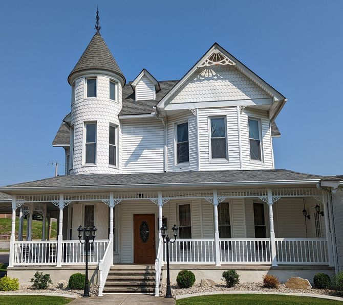 The front door of a house with a porch and plants in front of it.