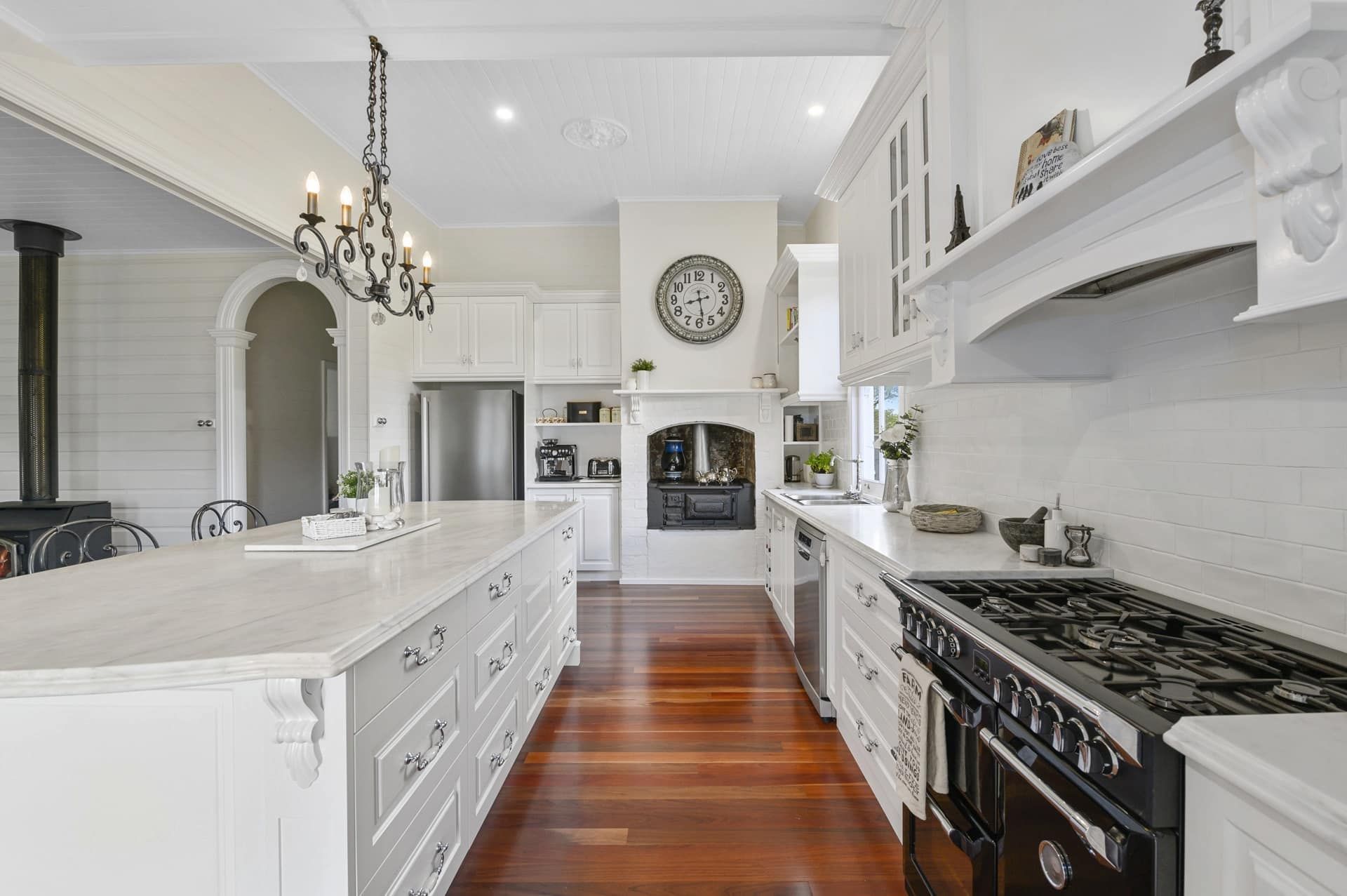 A Kitchen with White Cabinets, Hardwood Floors , a Stove and A Clock on The Wall — Sheridan Stone Aust in Yamba, NSW