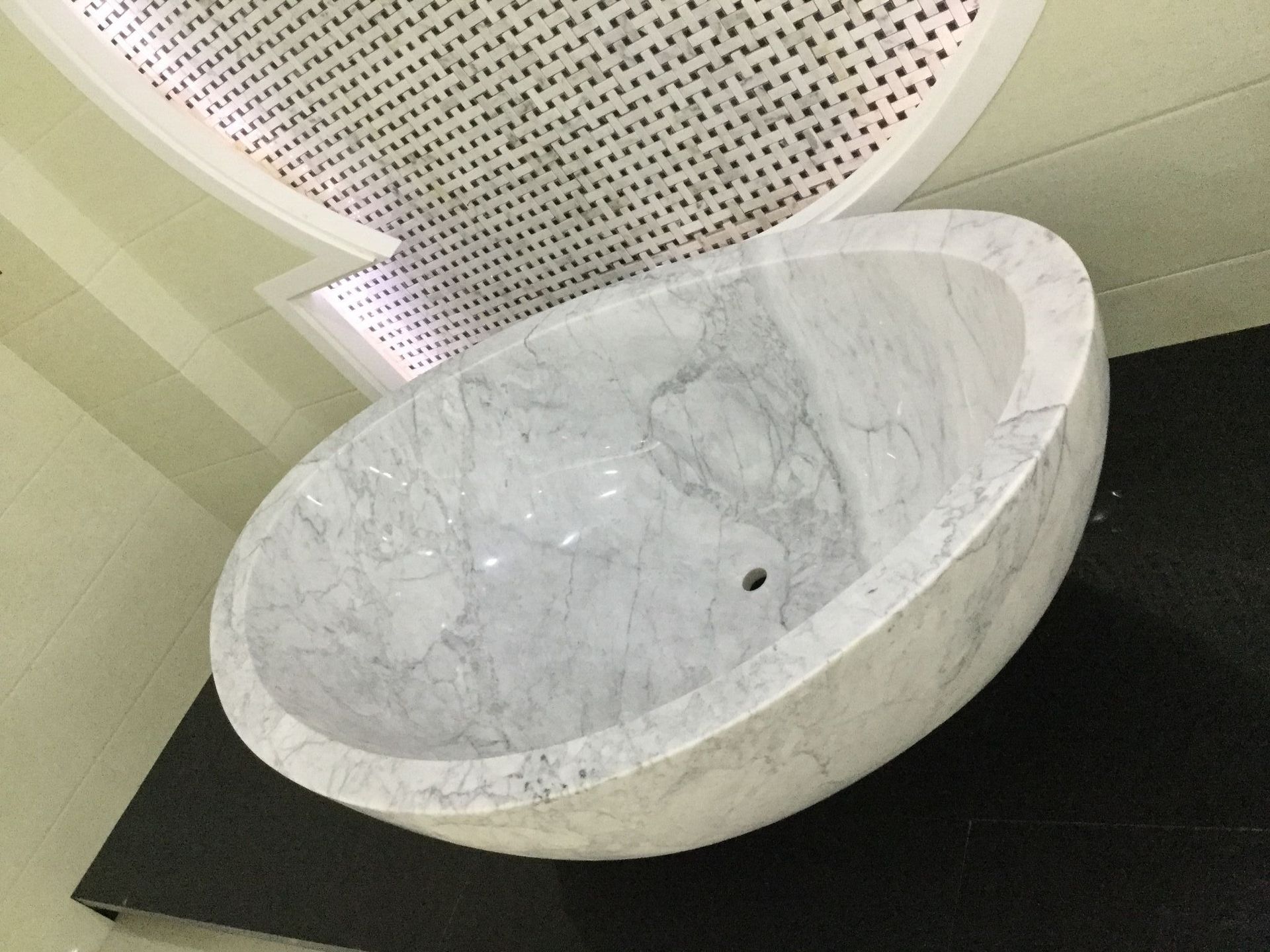 A White Marble Sink Is Sitting on A Black Counter in A Bathroom — Sheridan Stone Aust in Ballina, NSW