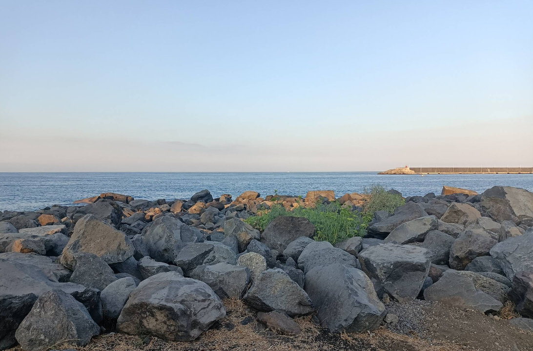 Costa rocciosa con oceano e cielo terso.