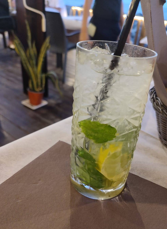 Mojito in un bicchiere decorato con limone e menta, su un tovagliolo marrone.