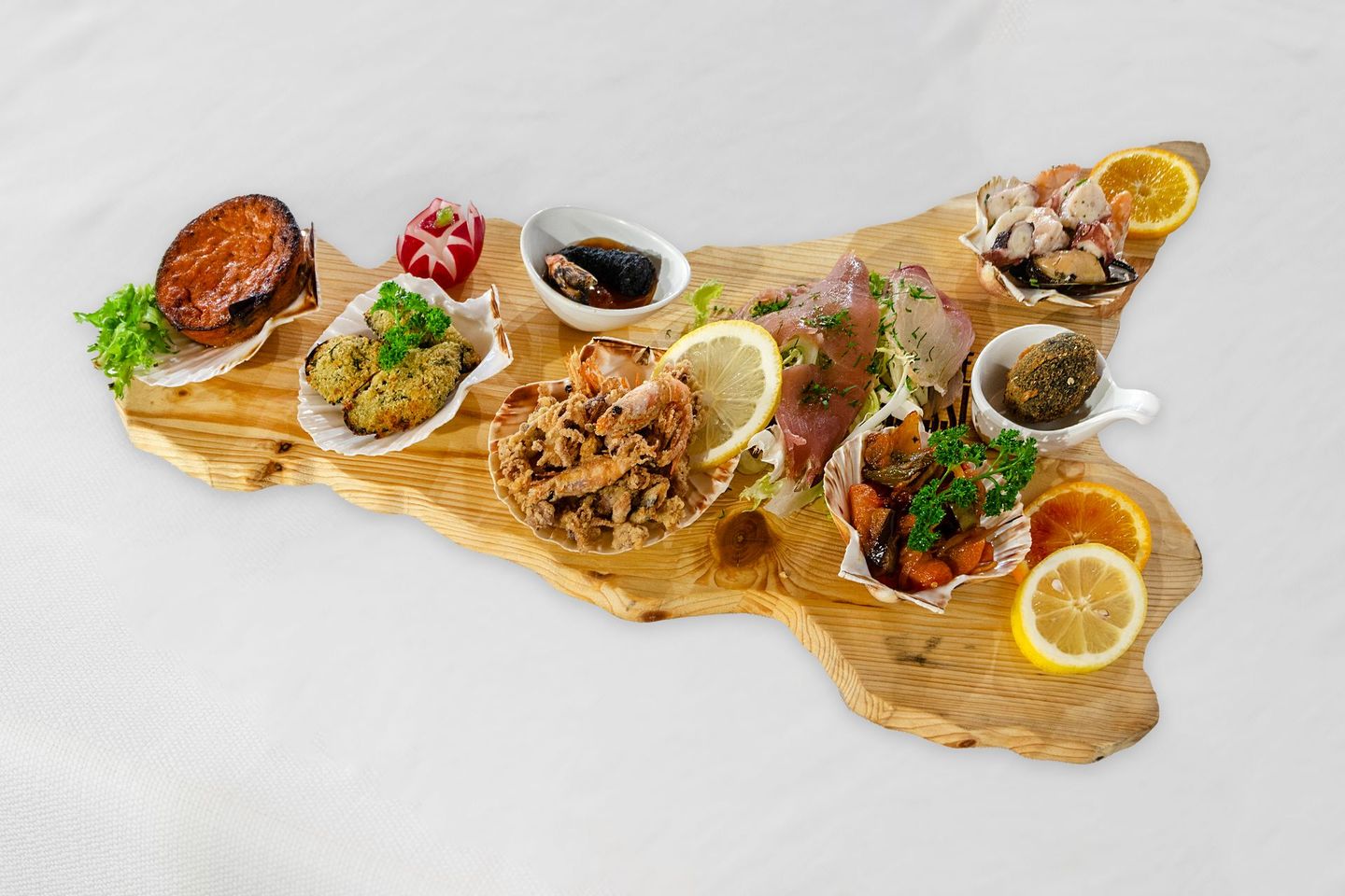 Antipasti disposti su un tagliere di legno a forma di Sicilia. Include frutti di mare, agrumi ed erbe aromatiche.