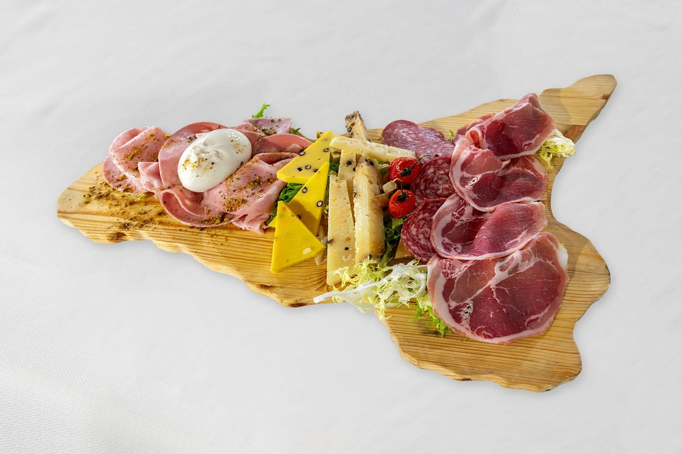 Tagliere di salumi a forma di Sicilia con carni, formaggi e verdure su una superficie bianca.