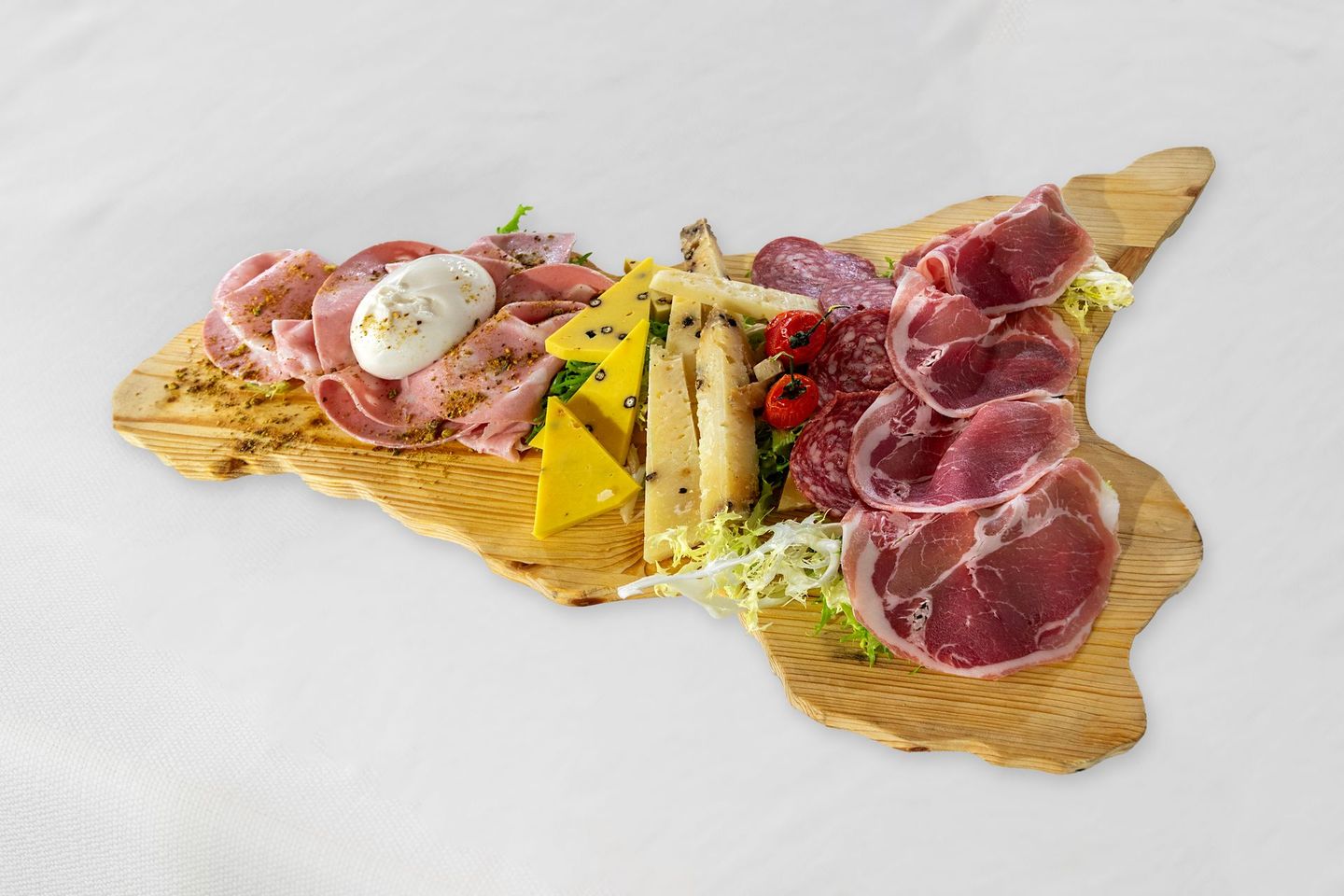 Tagliere di salumi a forma di Sicilia con salumi, formaggi e pomodori su un vassoio di legno.