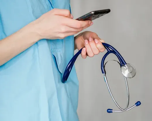 A nurse is holding a stethoscope and a cell phone.