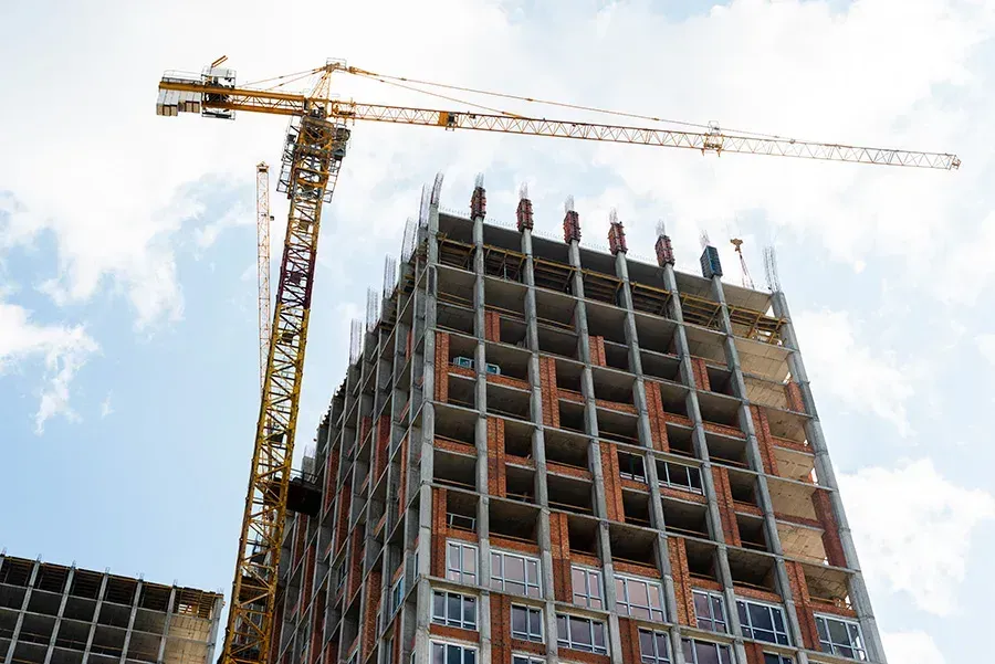 A large building is being built with a crane in the foreground.