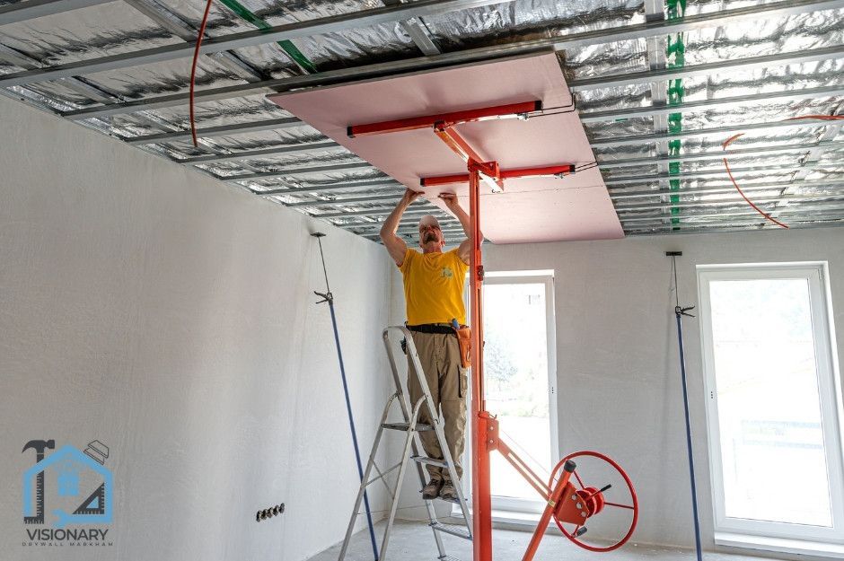 A commercial drywall installation contractor in Markham, Ontario hanging drywall on a condo ceiling using a machine to help lift the drywall sheets.