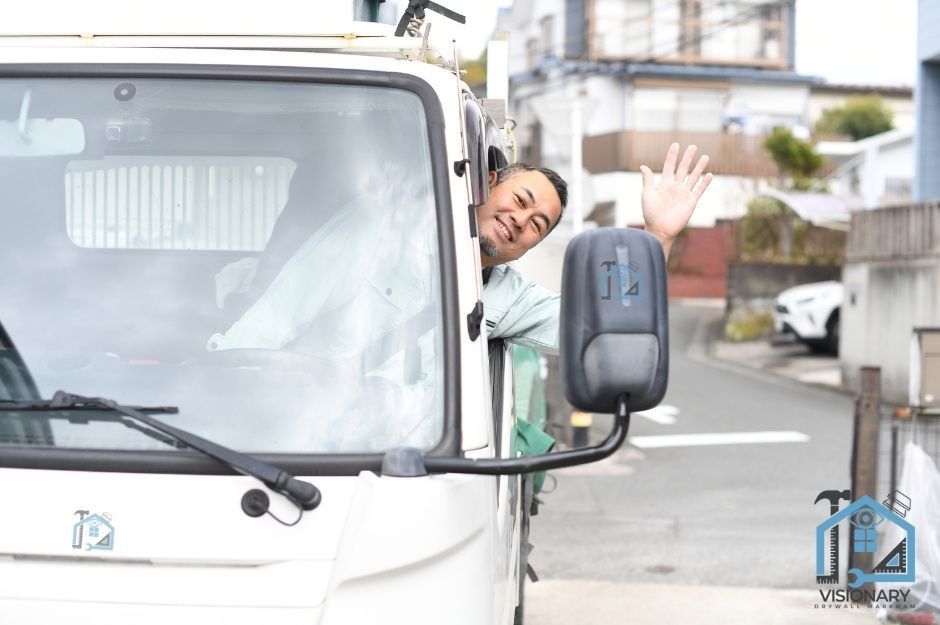 Happy male sheetrock delivery driver in a van delivering supplies to the worksite in Berczy Village.