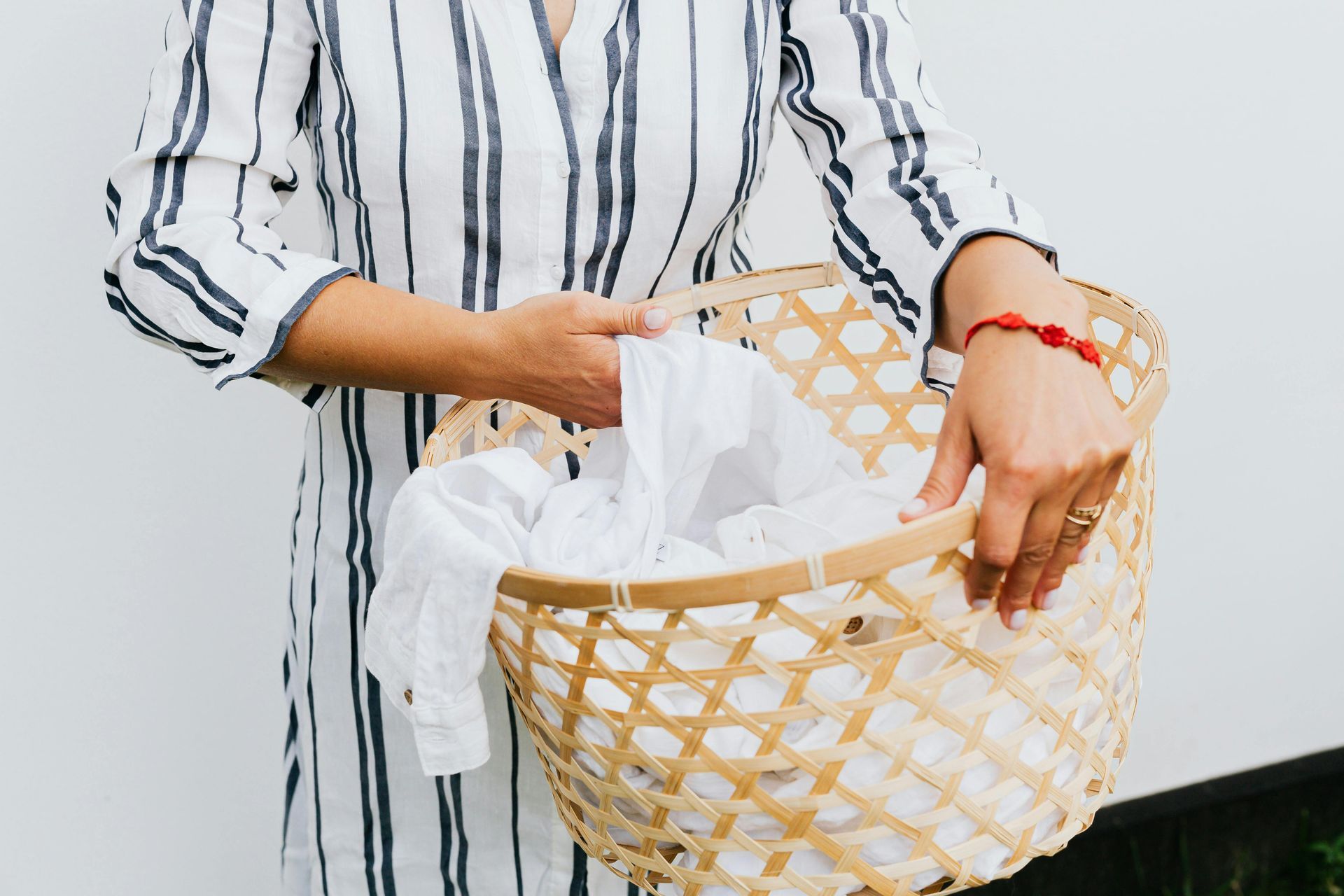 Person holding an item of white clothing out of a wicker basket.