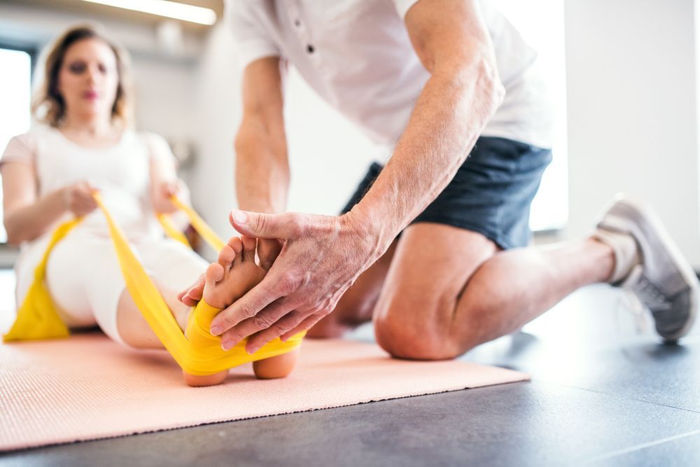 A Man is Stretching a Woman's Leg with a Rubber Band — Return to Performance Physiotherapy in Epsom, VIC