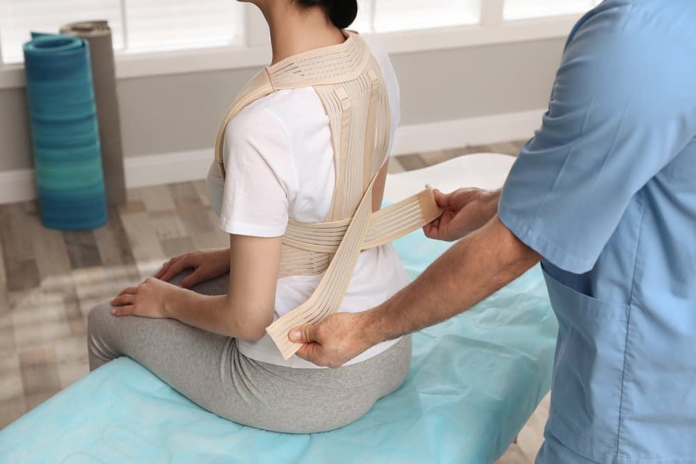 A Man is Putting a Posture Corrector on a Woman's Back — Return to Performance Physiotherapy in Castlemaine, VIC