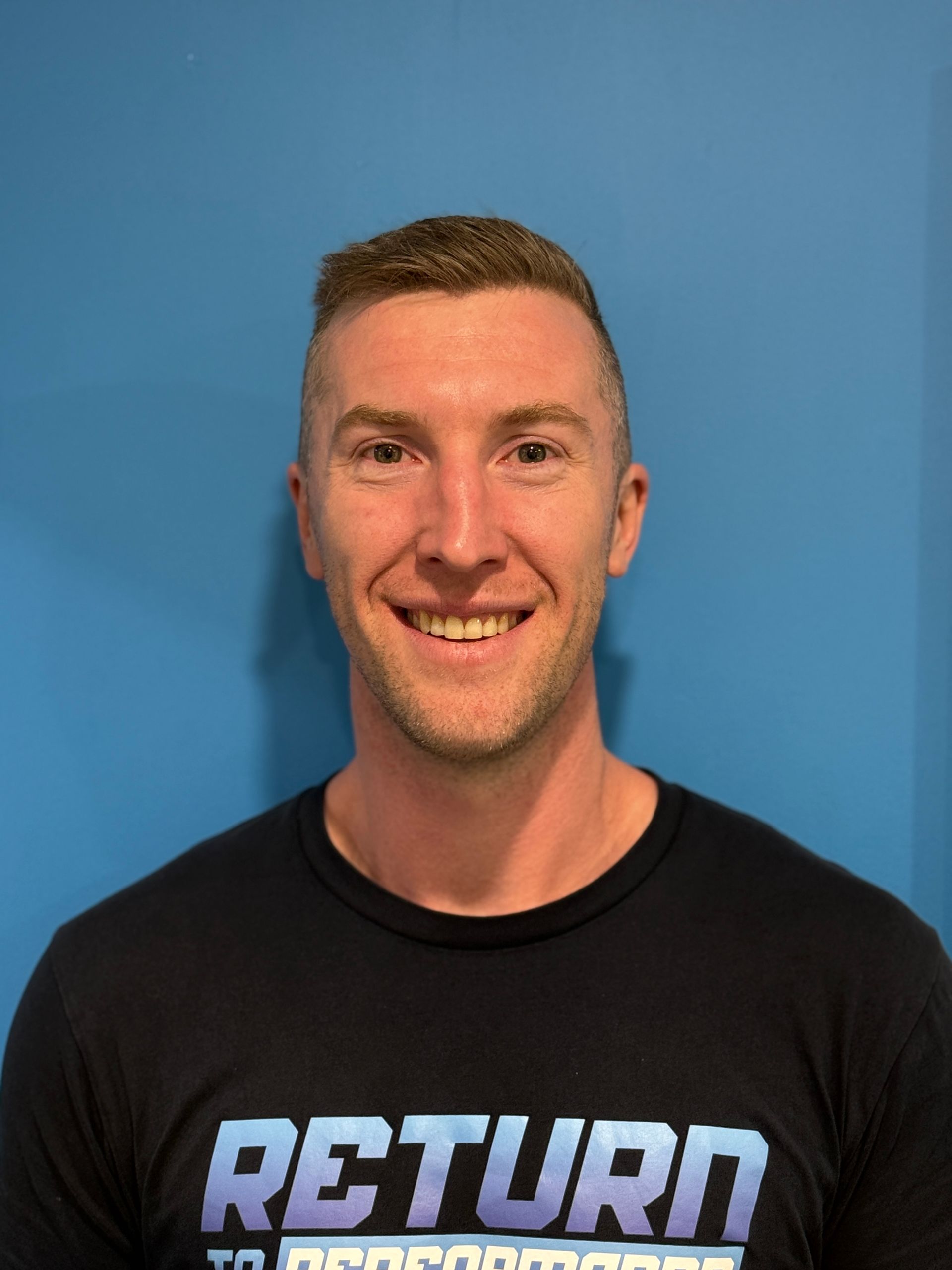 A Man Is Standing In A Gym With His Arms Crossed — Return to Performance Physiotherapy in Epsom, VIC