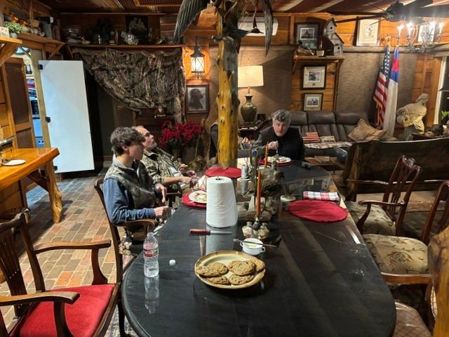 Two people seated at a rustic restaurant table with red placemats and plates of food