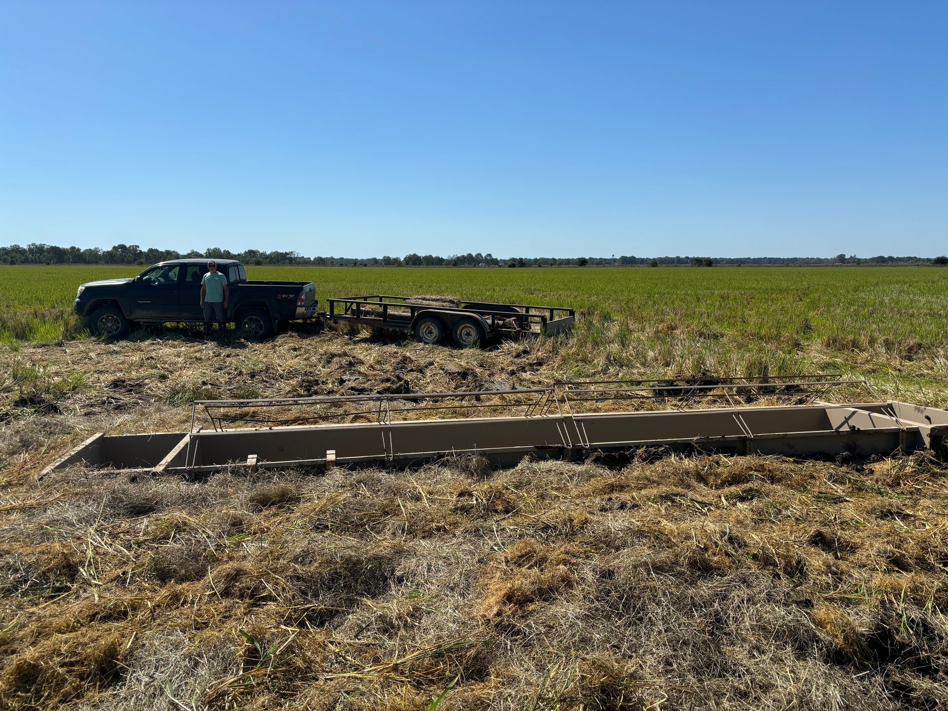 Tractor pulling a long planter across a dry field under a clear blue sky