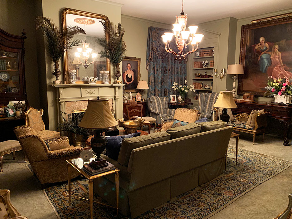 Elegant living room with chandelier, fireplace, sofa, armchairs, lamps, and framed art.