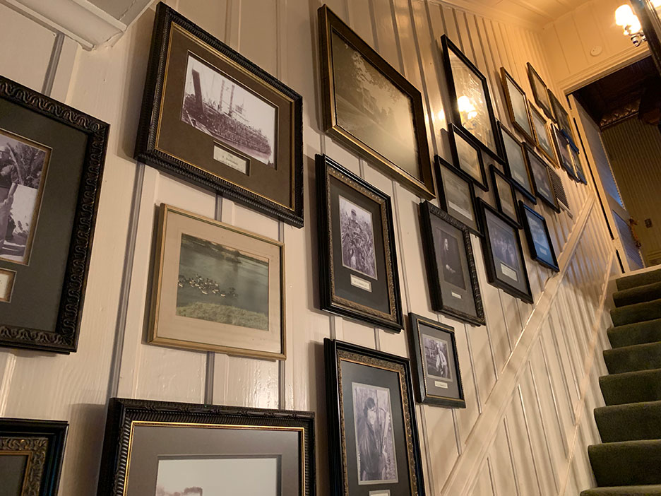 Framed photos line a stairway wall beside a green-carpeted staircase.