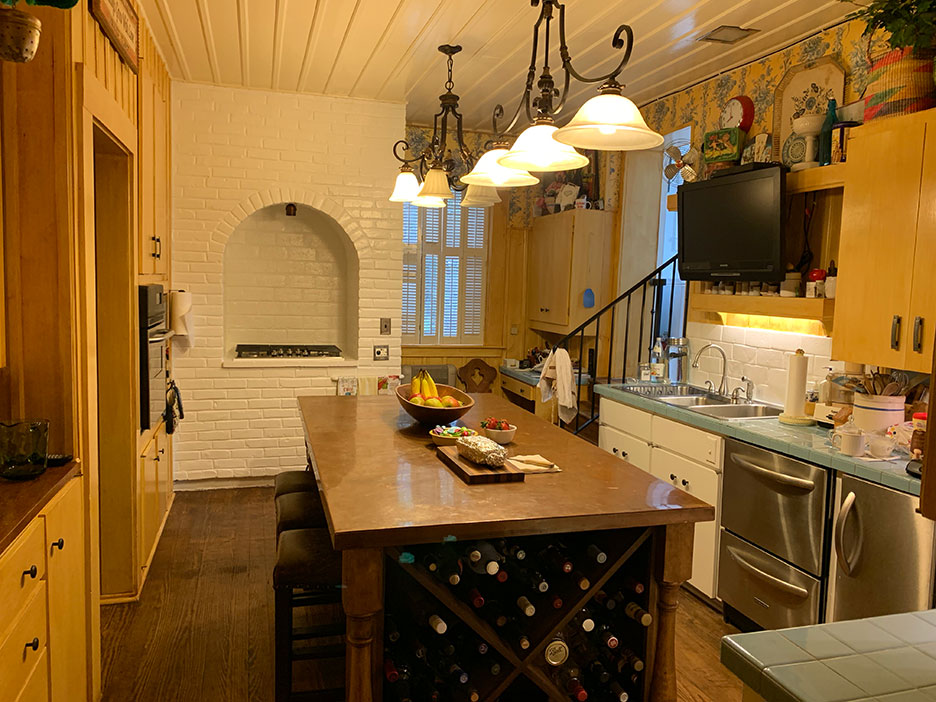 Bright kitchen with island, pendant lights, wine rack, stainless appliances, and arched brick oven niche