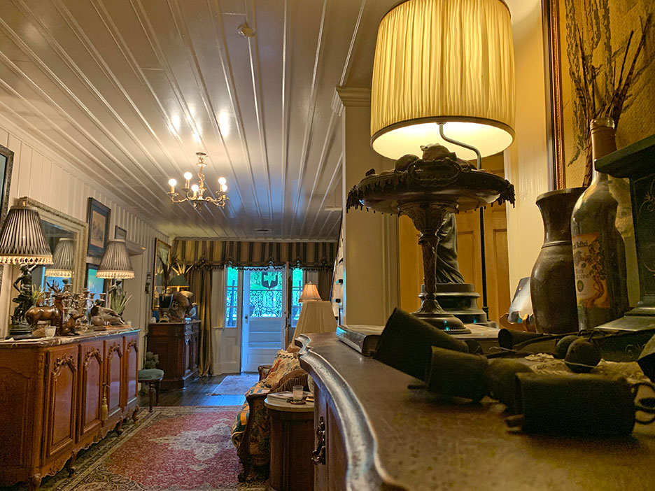 Elegant vintage living room with ornate lamps, wooden furniture, and a bright doorway at the back