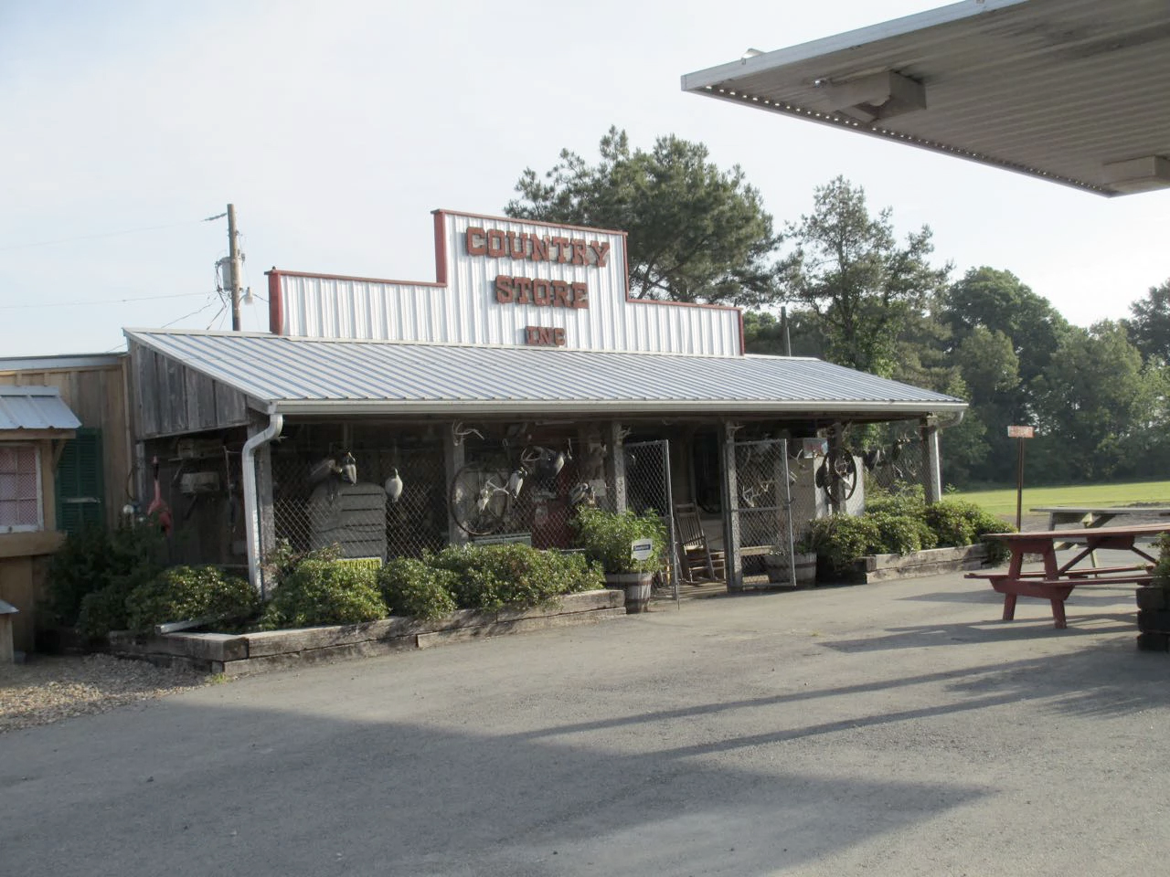 Small rustic roadside diner with a sign, porch, and picnic table under a cloudy sky.