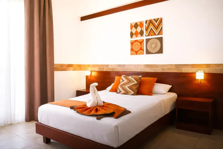 Habitación de hotel moderna con una cama bien hecha, detalles en naranja,