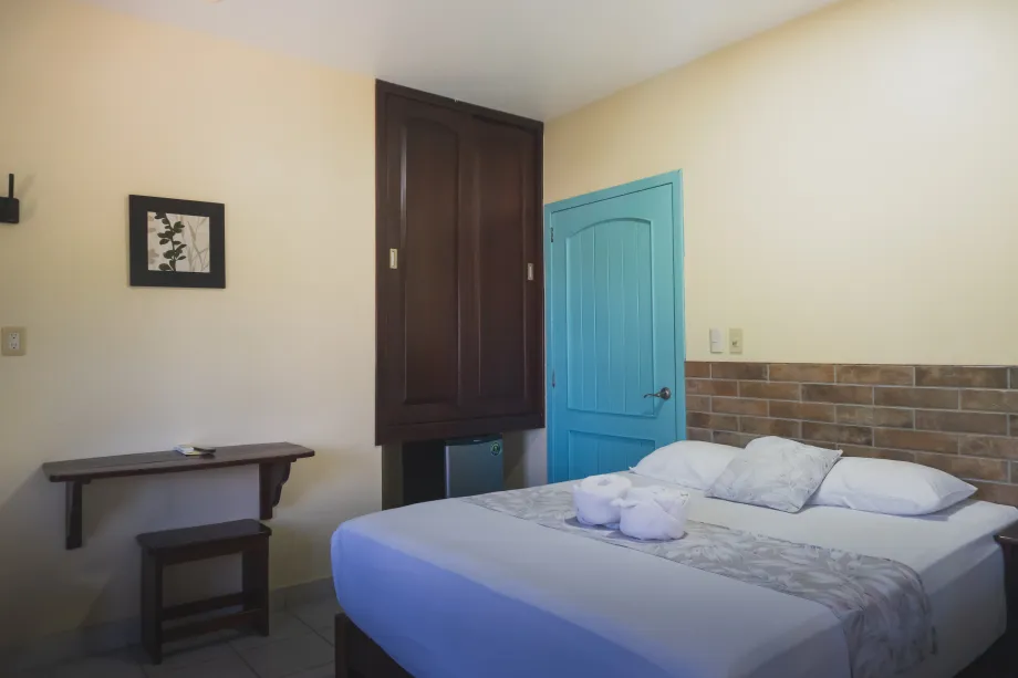 Habitación pequeña con una cama sin hacer, puerta azul.