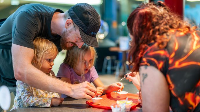Two children and an adult being led in a facilitated activity by ScienceWorks staff person